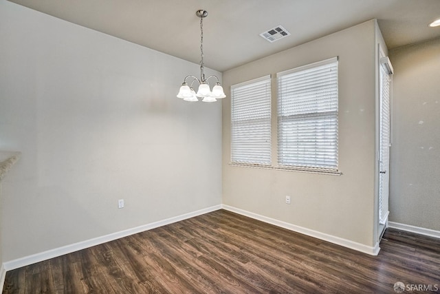 unfurnished dining area with dark wood-style flooring, a chandelier, and baseboards