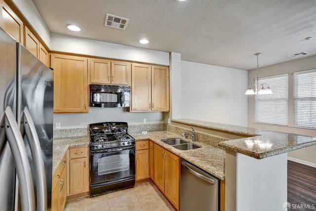 kitchen with black appliances, a sink, a peninsula, light stone countertops, and recessed lighting