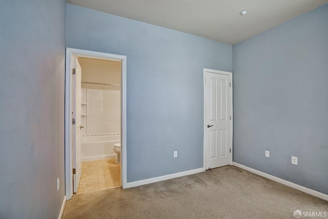 unfurnished bedroom with carpet floors, baseboards, and connected bathroom