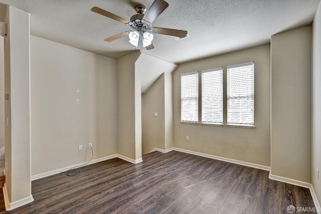 empty room with dark wood-style flooring, ceiling fan, a textured ceiling, and baseboards