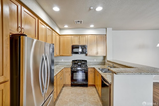 kitchen featuring black appliances, a peninsula, a sink, light stone countertops, and recessed lighting
