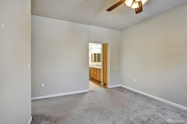 spare room with ceiling fan, light colored carpet, baseboards, and a sink