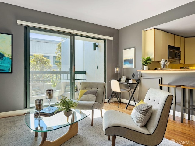 living area featuring baseboards and light wood finished floors