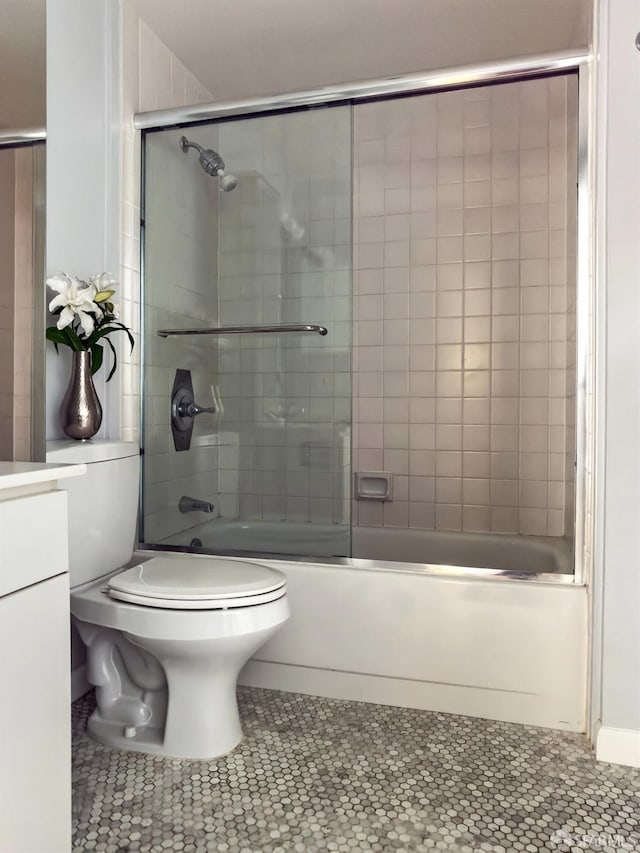 bathroom with enclosed tub / shower combo, vanity, and toilet