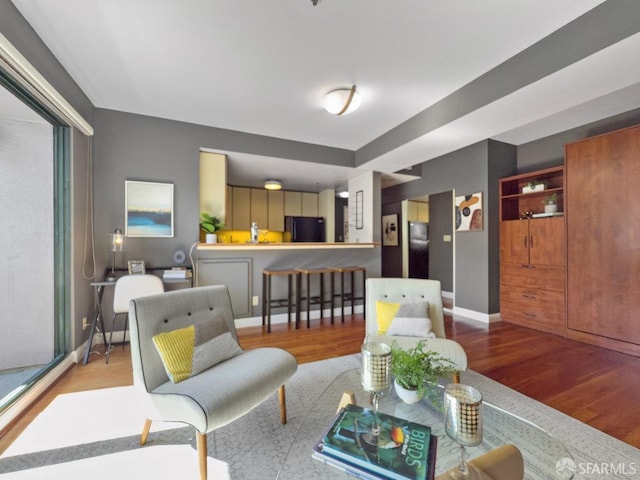 living area with baseboards and wood finished floors