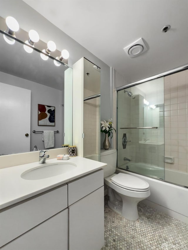 bathroom featuring toilet, combined bath / shower with glass door, vanity, and tile patterned floors