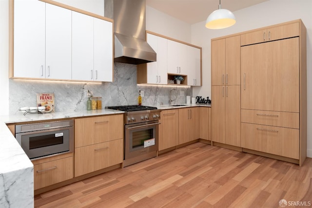 kitchen featuring exhaust hood, appliances with stainless steel finishes, decorative backsplash, pendant lighting, and sink