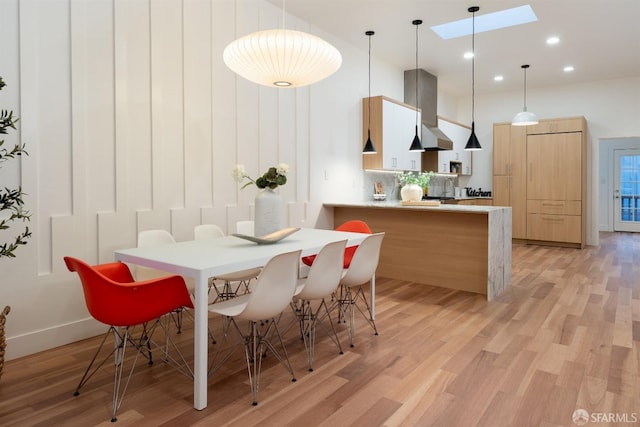 dining area with sink, light hardwood / wood-style flooring, and a skylight