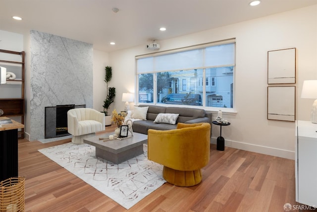 living room with a high end fireplace and light hardwood / wood-style floors