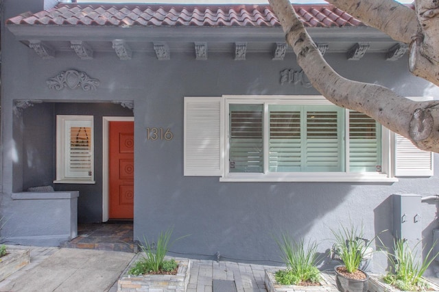 doorway to property featuring a tiled roof and stucco siding