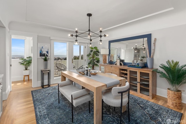 dining area with light wood-style flooring, a chandelier, and baseboards