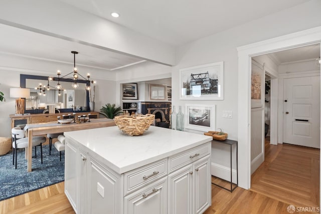 kitchen featuring a kitchen island, open floor plan, light wood-style floors, a fireplace, and white cabinetry