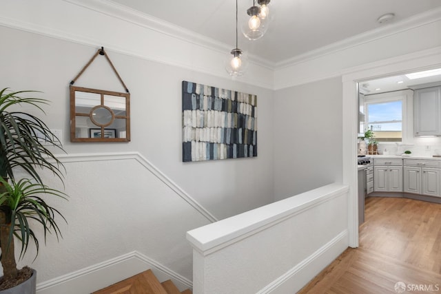 staircase with wood finished floors and crown molding