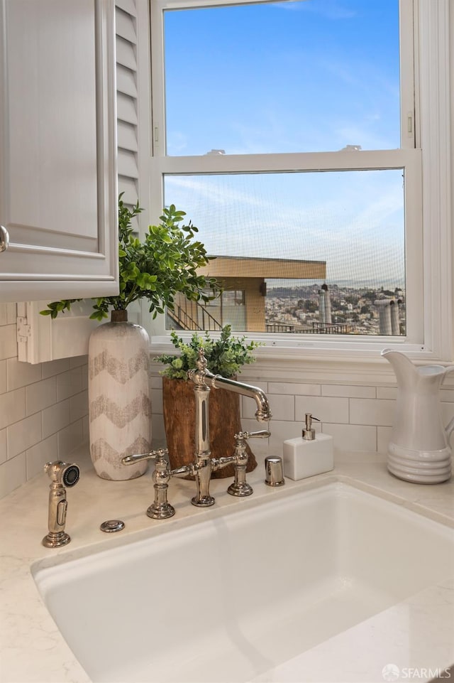 interior details with white cabinetry, a sink, and decorative backsplash