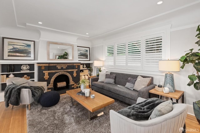 living room featuring crown molding, a fireplace, wood finished floors, and recessed lighting