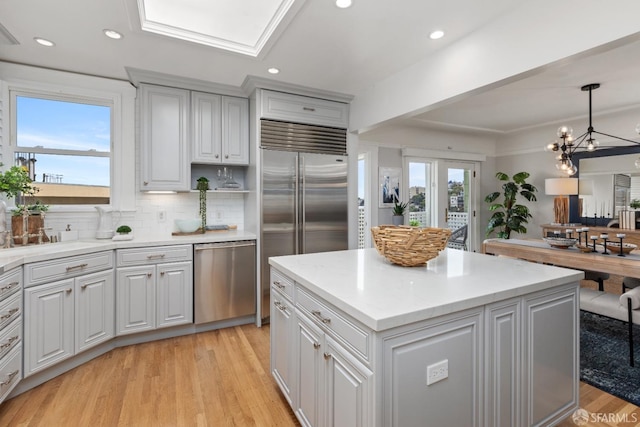 kitchen with recessed lighting, a kitchen island, appliances with stainless steel finishes, light wood-type flooring, and tasteful backsplash