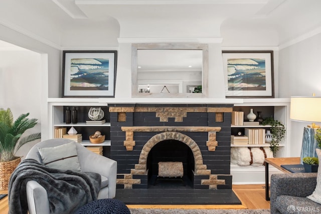 living area with built in shelves, a brick fireplace, and wood finished floors