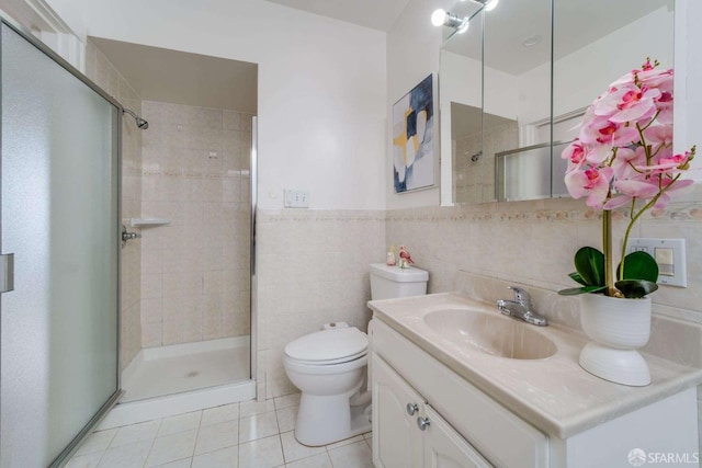 bathroom with toilet, tile walls, vanity, tile patterned floors, and a stall shower