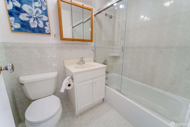 bathroom featuring enclosed tub / shower combo, toilet, tile walls, vanity, and tile patterned floors