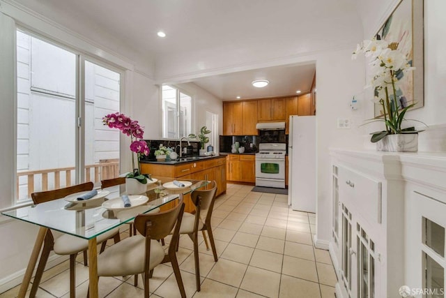 kitchen with light tile patterned flooring, white appliances, a sink, brown cabinets, and tasteful backsplash