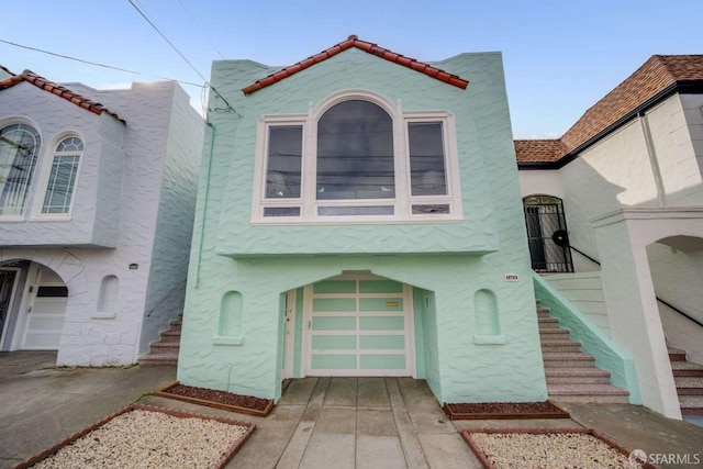 view of front of house with concrete driveway, stairway, and stucco siding