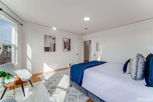 bedroom with wood finished floors, visible vents, and baseboards