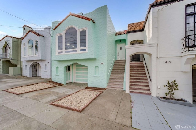 mediterranean / spanish-style home featuring stucco siding, a tiled roof, and stairs