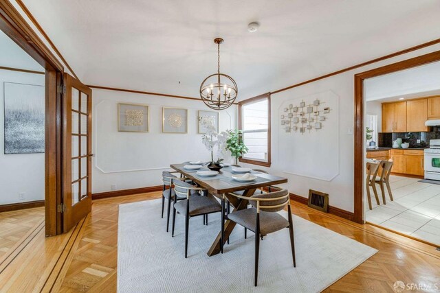 dining space featuring baseboards, visible vents, a chandelier, and crown molding