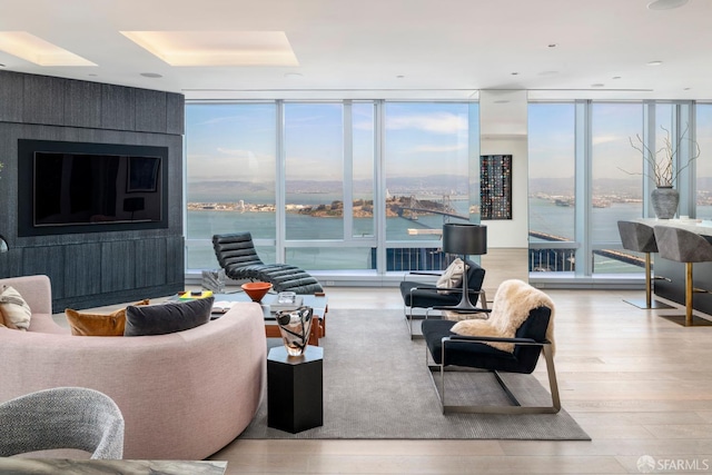 living room with a water view, expansive windows, and wood finished floors