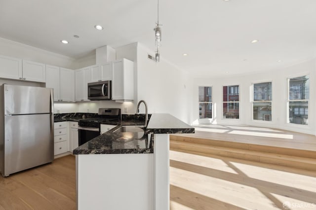 kitchen featuring sink, white cabinetry, light hardwood / wood-style flooring, appliances with stainless steel finishes, and kitchen peninsula