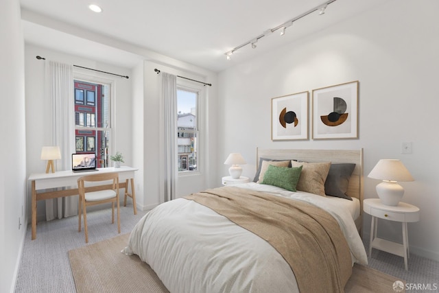 carpeted bedroom with rail lighting