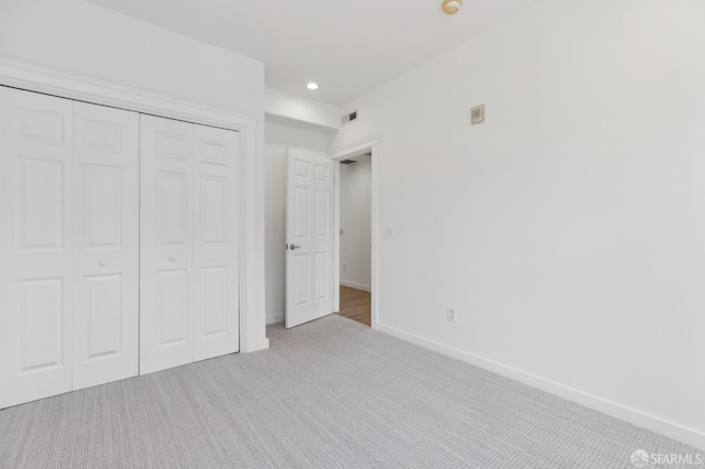 unfurnished bedroom featuring light carpet and a closet