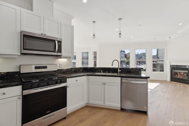 kitchen featuring pendant lighting, white cabinetry, sink, dark stone counters, and stainless steel appliances