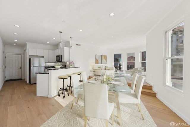 dining room featuring light wood-type flooring and crown molding