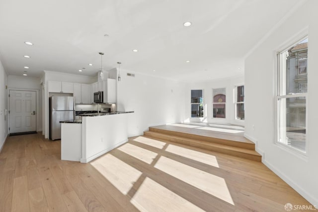 kitchen with decorative light fixtures, ornamental molding, appliances with stainless steel finishes, light hardwood / wood-style floors, and white cabinets