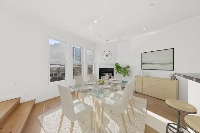 dining space with crown molding and light hardwood / wood-style flooring