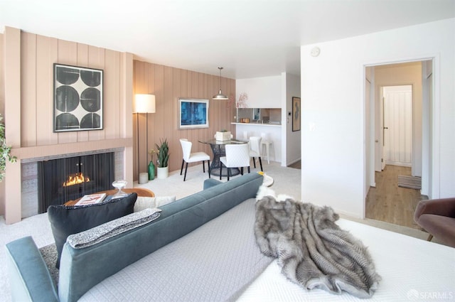 living room featuring wood walls and a warm lit fireplace