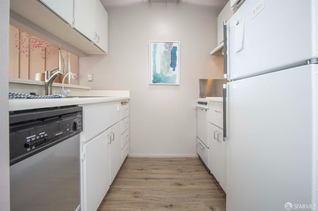 kitchen with white appliances, light wood-style flooring, a sink, light countertops, and white cabinets