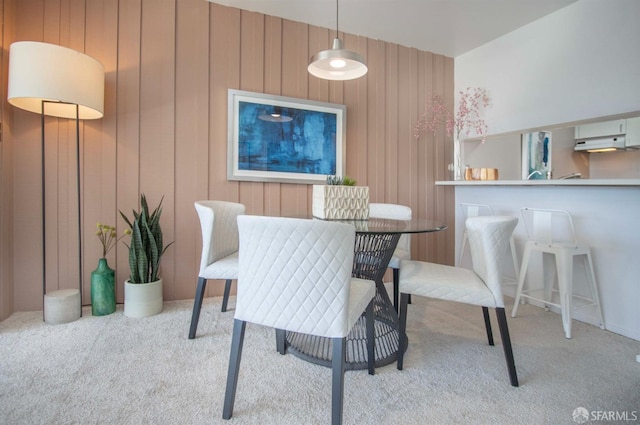 dining space with carpet flooring and wood walls