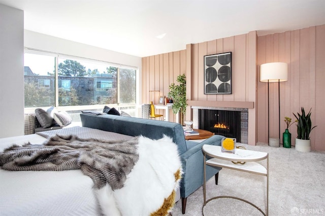 carpeted bedroom with a brick fireplace and wood walls