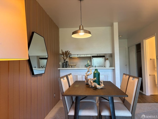 dining area with carpet floors and wood walls