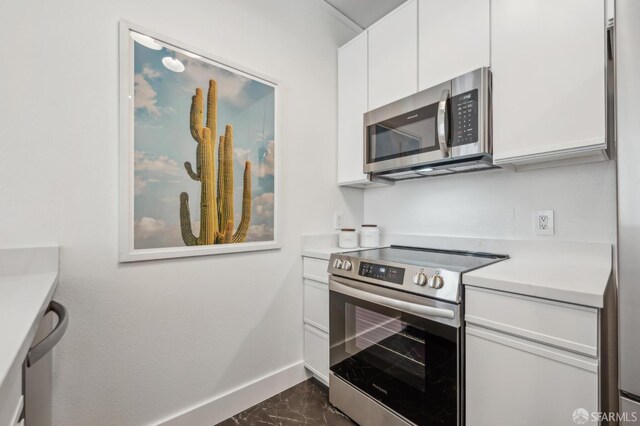 1805 Fillmore St Unit 302, San Francisco, CA 94115 - kitchen featuring stainless steel appliances, baseboards, white cabinetry, light countertops, and dark marble finish floors