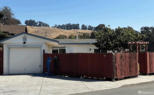 view of front of property featuring a garage, concrete driveway, and fence