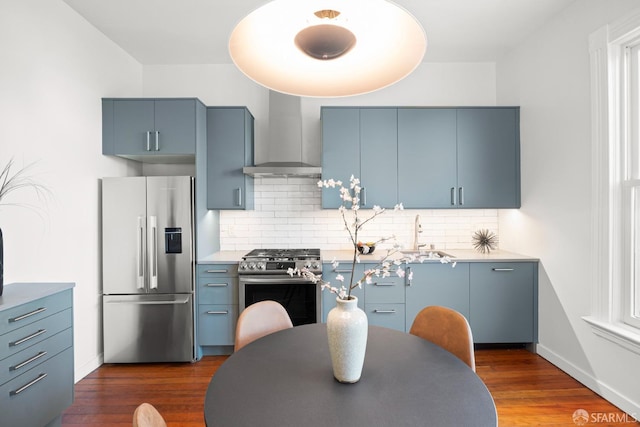 2553 Folsom St Unit A, San Francisco, CA 94110 - kitchen featuring appliances with stainless steel finishes, wall chimney exhaust hood, a sink, decorative backsplash, and blue cabinetry