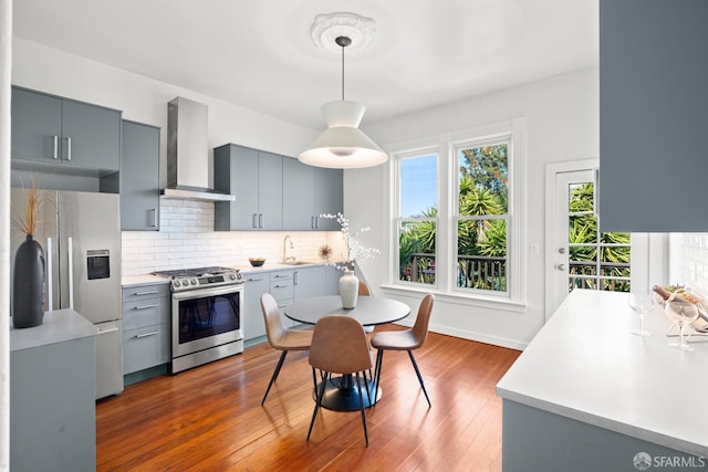 2553 Folsom St Unit A, San Francisco, CA 94110 - kitchen featuring appliances with stainless steel finishes, wall chimney exhaust hood, gray cabinetry, and healthy amount of natural light