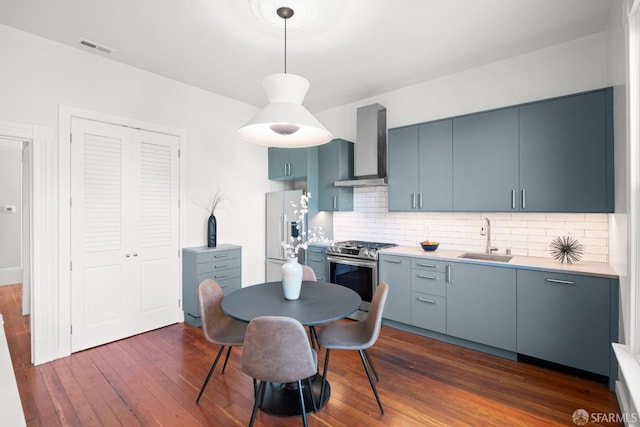 2553 Folsom St Unit A, San Francisco, CA 94110 - kitchen featuring wall chimney exhaust hood, stainless steel range with gas stovetop, white fridge with ice dispenser, a sink, and dark wood-style floors