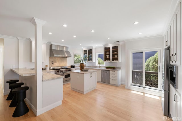 803 Vermont St, San Francisco, CA 94107 - kitchen featuring appliances with stainless steel finishes, wall chimney range hood, crown molding, healthy amount of natural light, and light wood-type flooring