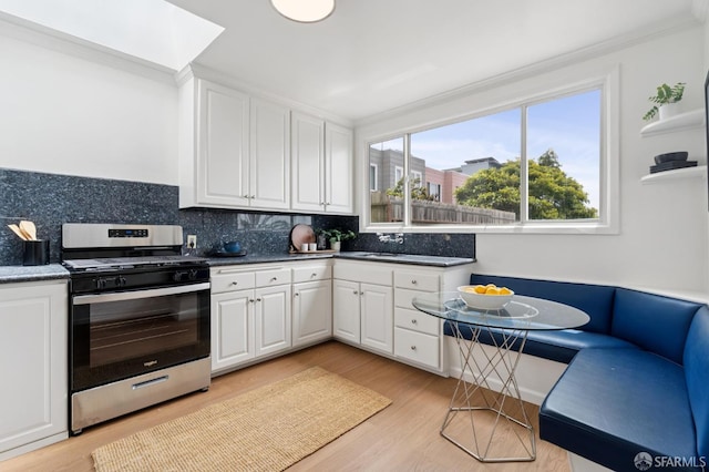 2421 Quintara St, San Francisco, CA 94116 - kitchen with gas range, white cabinetry, decorative backsplash, crown molding, and light wood-style flooring