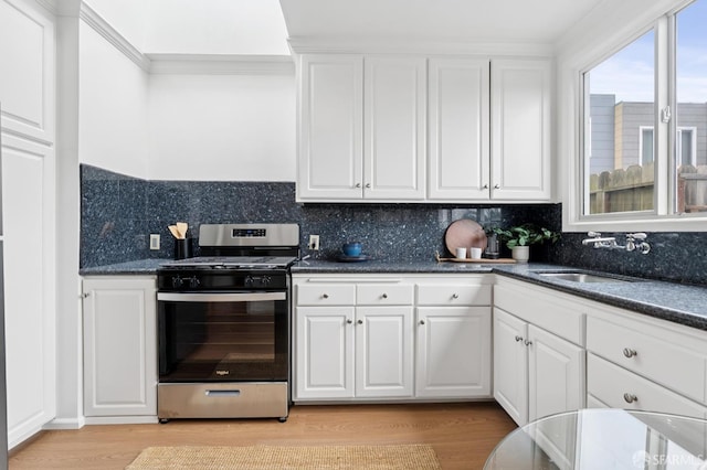 2421 Quintara St, San Francisco, CA 94116 - kitchen featuring stainless steel range with gas stovetop, dark countertops, white cabinetry, light wood-type flooring, and ornamental molding