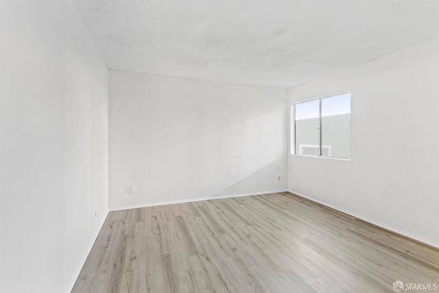 unfurnished room with a textured ceiling, baseboards, and light wood-style floors